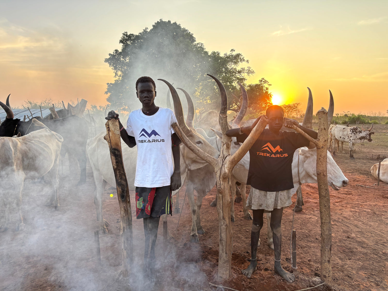 “Mundari tribe youth wearing TREKARIUS t-shirts South Sudan sunset”.