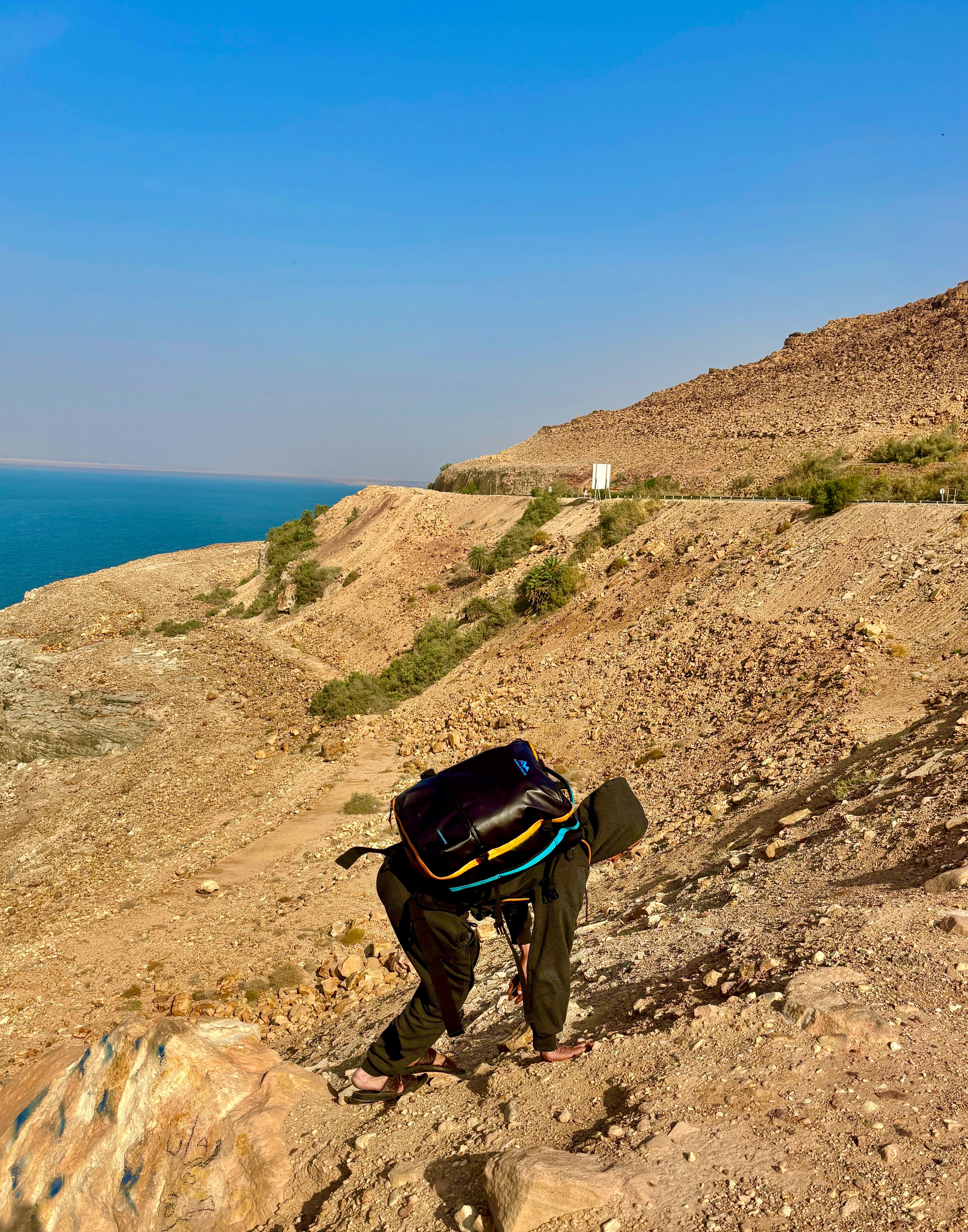 trekarius hiking on a rocky trail with a scenic view of the ocean and mountains in dead sea Jordan.