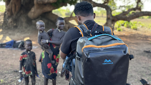 man wearing a trekarius backpack taking a photo of the mundari tribe in south sudan 