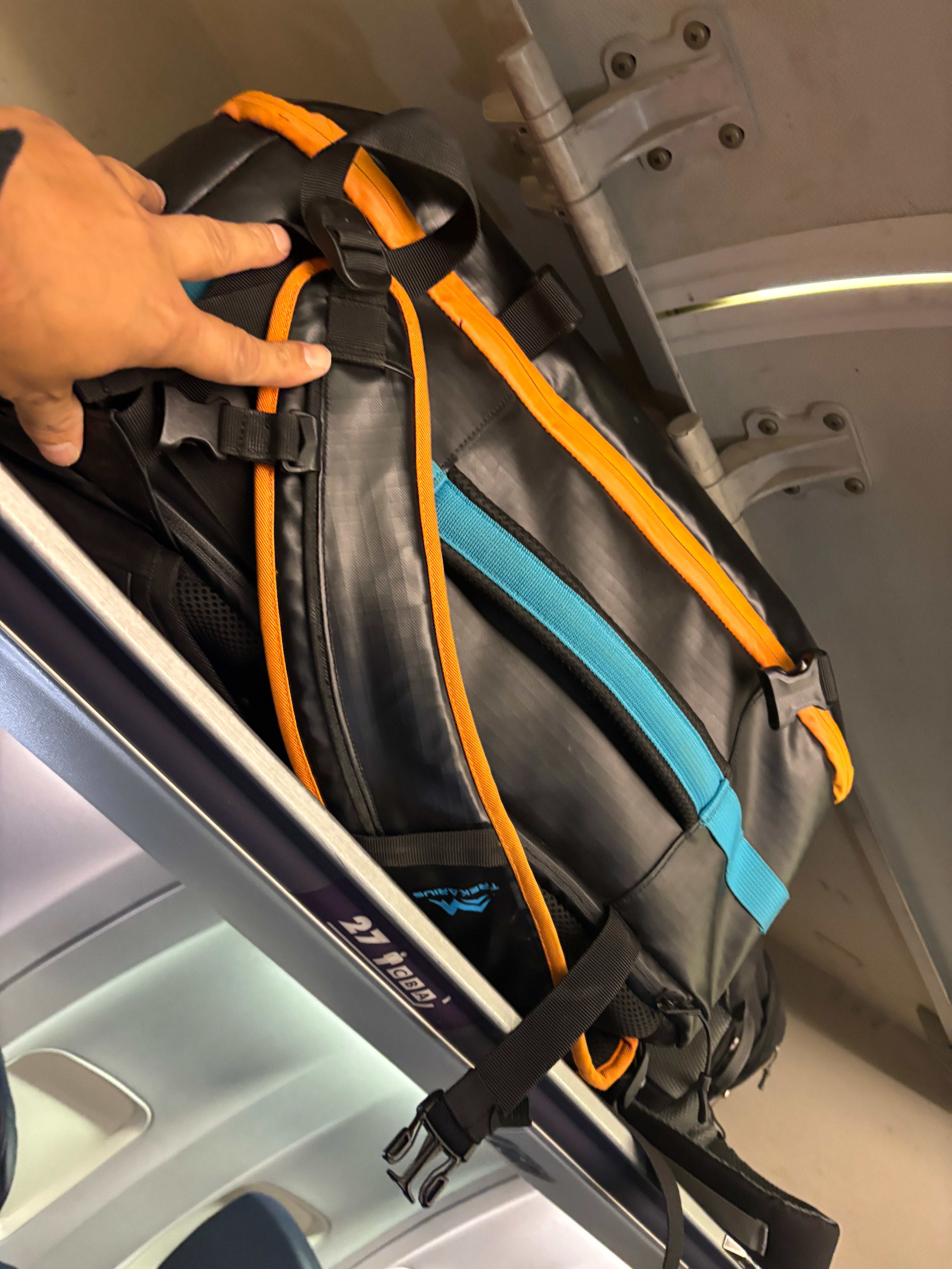 TREKARIUS 35L backpack stored above the seat in a plane cabin as carry-on